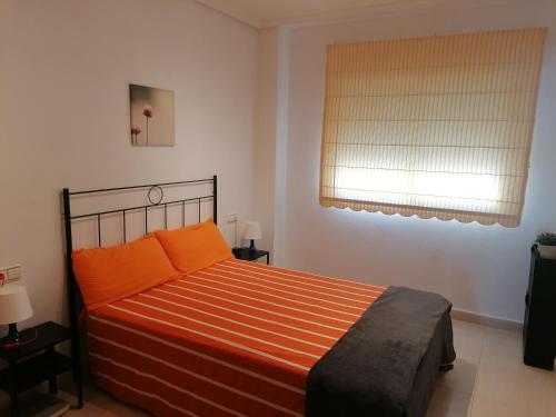ein Schlafzimmer mit einem Bett mit orangefarbenen Kissen und einem Fenster in der Unterkunft Sea and Relax Apartment By MM in Torrevieja