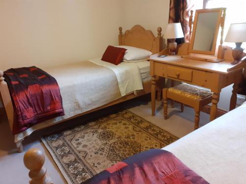 a bedroom with two beds and a desk and a mirror at Cornode Cottage in Garrykennedy