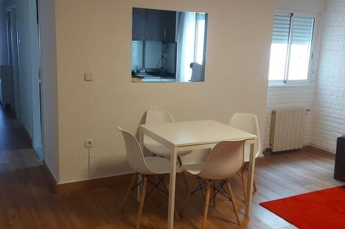 a white dining room table with white chairs and a mirror at Precioso piso-apartamento en barrio de Zaragoza in Zaragoza