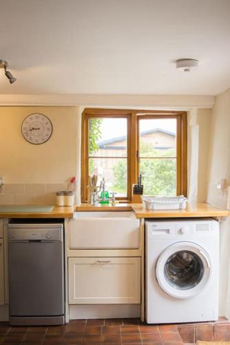 a kitchen with a washing machine and a window at Batney Farm Cottage, Meshaw, South Molton in South Molton