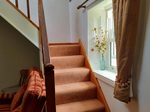 a stairway with a vase of flowers in a window at Lackaroe Cottage in Garrykennedy