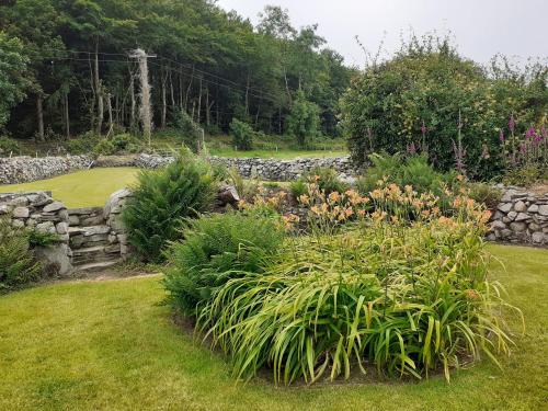 a garden with flowers and a stone wall at Lackaroe Cottage in Garrykennedy