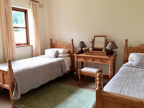 um quarto com 2 camas e uma mesa com um espelho em Fraoch Cottage em Garrykennedy