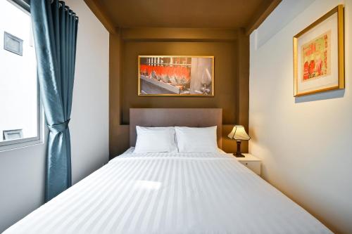 a bedroom with a white bed and a window at The Noble Swan Wood Park Hotel in Ho Chi Minh City