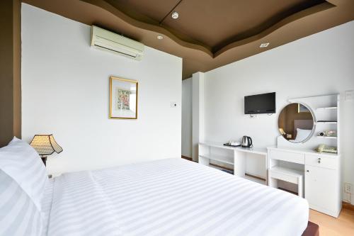 a white bedroom with a bed and a mirror at The Noble Swan Wood Park Hotel in Ho Chi Minh City