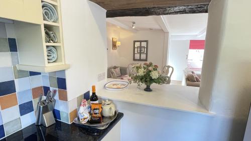 a kitchen with a counter with a vase of flowers at The Nook - Charming cottage, modern living with original features, perfect private garden in Dittisham