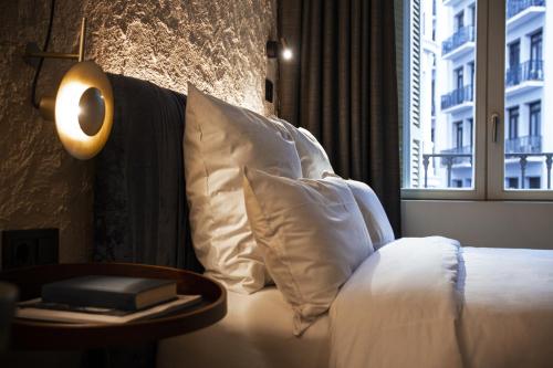 a bedroom with a bed with white pillows and a table at Letoh Letoh Gran Vía in Madrid