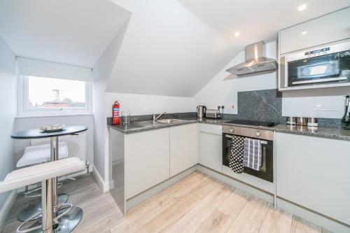 a kitchen with white cabinets and a sink and a table at 14 Helena House One Bedroom Apartment in Reading