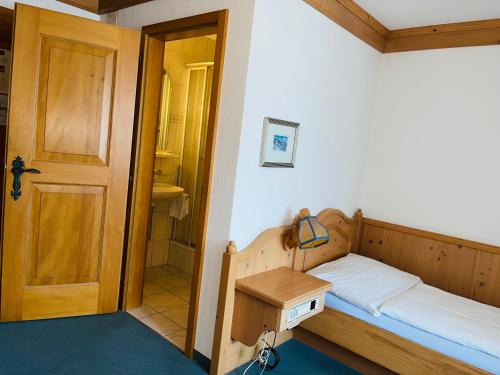 a small bedroom with a bed and a wooden door at Hotel Sternen Worb in Worb