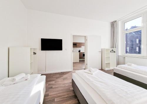um quarto branco com 2 camas e uma televisão de ecrã plano em RAJ Living - 1 Room Monteur Apartments - 25 Min Messe DUS em Duisburg