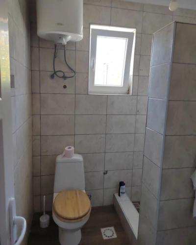 a small bathroom with a toilet and a window at Apartmani Jela in Sombor