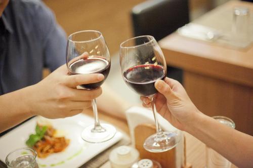 two people are holding glasses of red wine at The Exchange Regency Residence Hotel Managed by HII in Manila