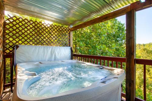 un bain à remous sur une terrasse avec pergola dans l'établissement Pet-friendly Rustic Cabin with Game Room and Deck, à Pigeon Forge