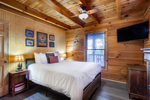 une chambre avec un lit et une télévision à écran plat dans l'établissement Pet-friendly Rustic Cabin with Game Room and Deck, à Pigeon Forge