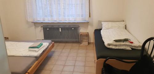 Habitación pequeña con 2 camas y ventana en Joanna Apartment - Schwetzingen 2 en Schwetzingen
