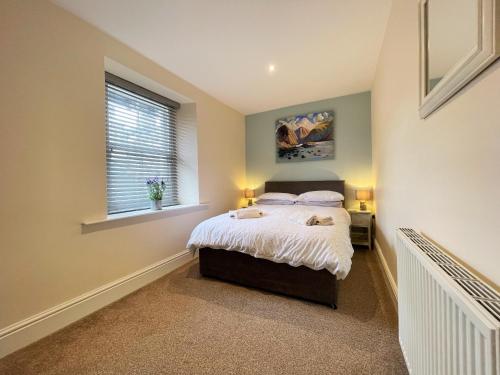 1 dormitorio con cama y ventana en Arthurs Cottage -Charming Courtyard Cottage in the heart of Kendal, The Lake District, en Kendal