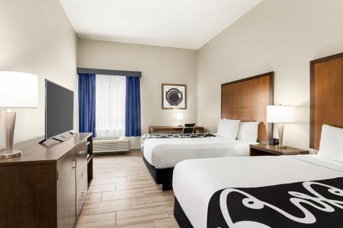 a hotel room with two beds and a flat screen tv at La Quinta by Wyndham Brownsville North in Brownsville