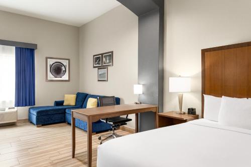 a hotel room with a bed and a desk and a couch at La Quinta by Wyndham Brownsville North in Brownsville