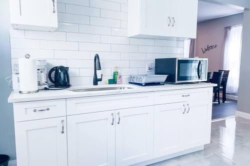 a white kitchen with a sink and a microwave at The Haines Villa in Niagara Falls