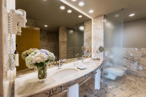 a bathroom with a sink with a vase of flowers at The Lince Azores in Ponta Delgada