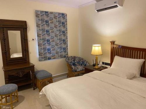 1 dormitorio con cama, espejo y silla en 1 BHK Luxury Beachside Homestay in South Goa en Betalbatim