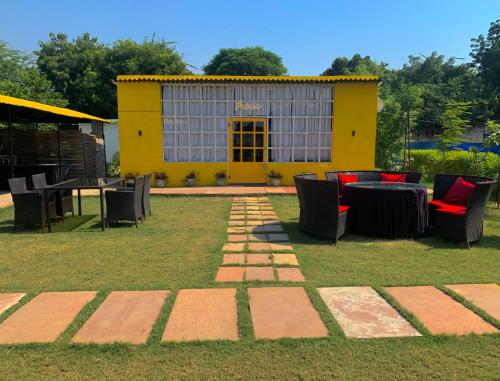 a yellow building with tables and chairs in a yard at Agra Camps and Resort in Agra