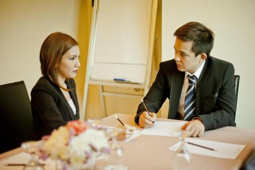 a man and woman sitting at a table at The Exchange Regency Residence Hotel Managed by HII in Manila