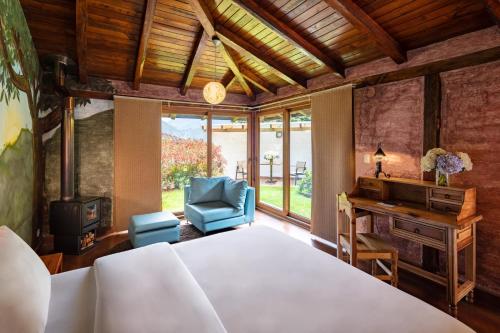 a bedroom with a bed and a desk and a chair at Luna Volcán, Adventure SPA in Baños