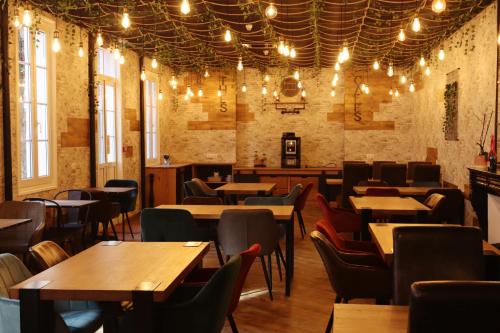 un restaurant avec des tables en bois, des chaises et des lumières dans l'établissement Hôtel & Restaurant Le Patio VICHY, à Vichy