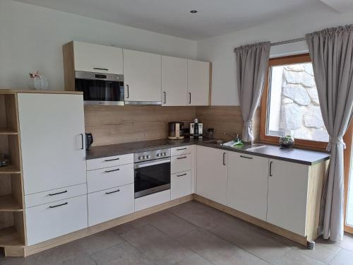 a kitchen with white cabinets and a window at Ferienwohnung Widmann in Jochberg