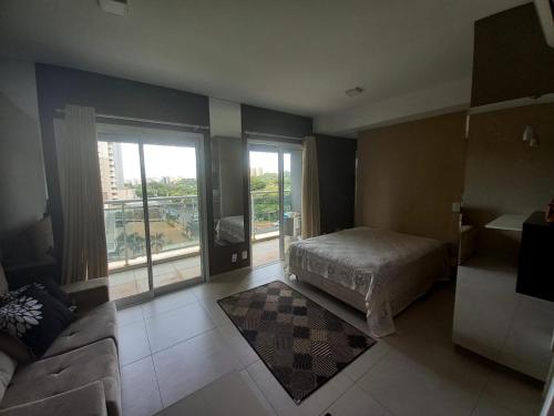 um quarto com uma cama, um sofá e uma janela em Flat Duo JK. Lindo e completo em Sao Jose do Rio Preto