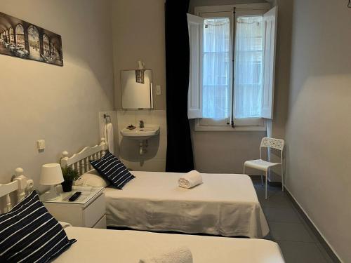 a small bedroom with two beds and a sink at Hostal Parisien Las Ramblas in Barcelona