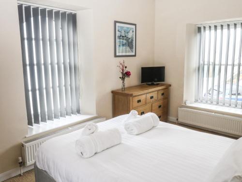 a bedroom with two towels on a bed with windows at 1 Greenswood Court in Brixham