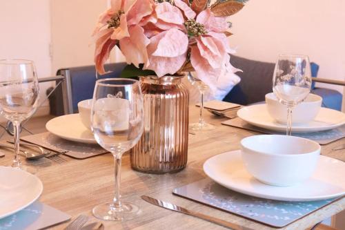a wooden table with plates and glasses and a vase with flowers at Cozy Family Stay with Free Parking and WiFi in Knowsthorpe