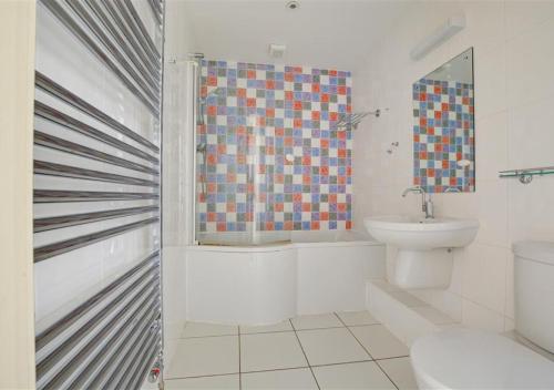 a bathroom with a toilet and a shower and a sink at The Lookout in Saundersfoot