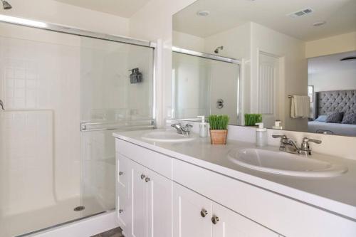 a white bathroom with two sinks and a shower at Spacious Modern Home in Sierra Lakes Fontana in Fontana