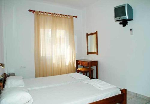 パレオコラにあるGiorgos Apartmentsのベッドルーム1室(ベッド2台、デスク、テレビ付)
