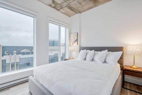 a bedroom with a large white bed and a large window at Initial / Fleuriste +Parking / Centre-ville Qc in Quebec City