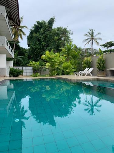 a swimming pool with turquoise water and palm trees at Anveela in Beruwala