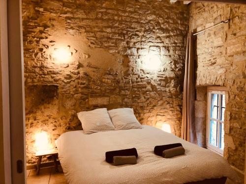 - une chambre avec un lit blanc et un mur en pierre dans l'établissement Le MOKA Charmant Appartement au coeur de ville, à Nîmes