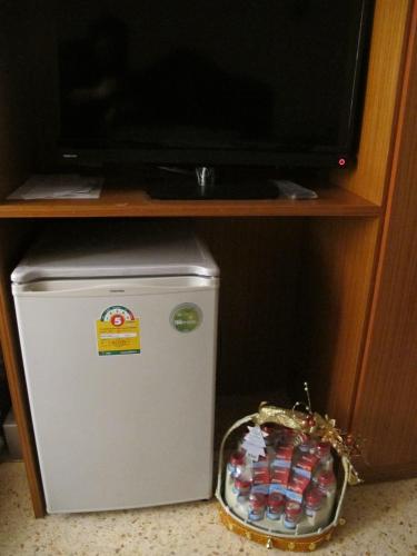 a small refrigerator sitting under a tv in a kitchen at The Star Hotel in Udon Thani