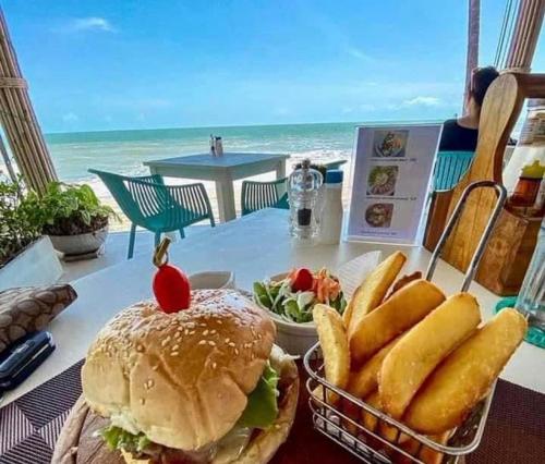 a table with a sandwich and a basket of french fries at Le Petit Saint Tropez in Khanom