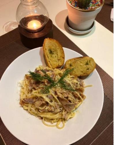 a white plate of pasta with bread and toast at Le Petit Saint Tropez in Khanom