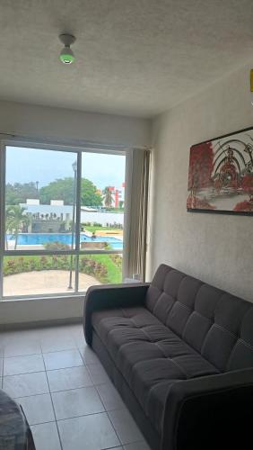 a living room with a couch and a large window at Renta departamento por día en Acapulco in Acapulco