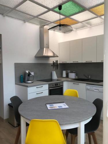 a kitchen with a table and yellow chairs at Bel appartement avec cour classé 3* Angelus 4P in Étaples