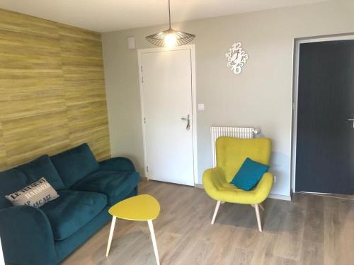 a living room with a blue couch and a yellow chair at Bel appartement avec cour classé 3* Angelus 4P in Étaples