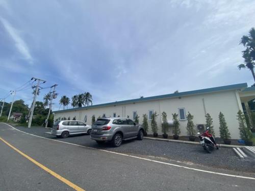 two cars parked in a parking lot next to a building at Le Petit Saint Tropez in Khanom