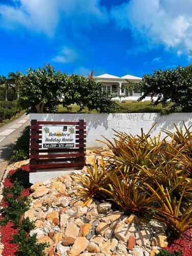 a sign in front of a house with plants at Holiday Home Belvedere in Dickenson Bay
