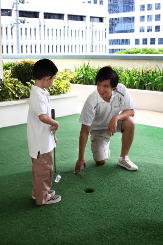a man and a young boy playing a game of golf at The Exchange Regency Residence Hotel Managed by HII in Manila