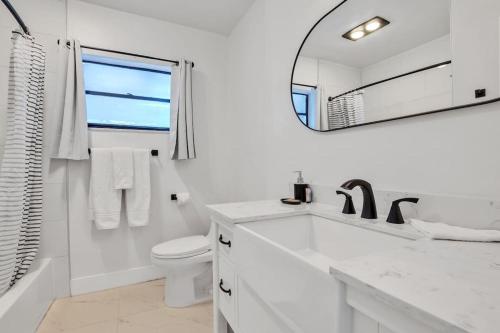 a white bathroom with a sink and a mirror at NEW! 3b/2ba: pool, hot tub, and cotton candy maker in Fort Lauderdale